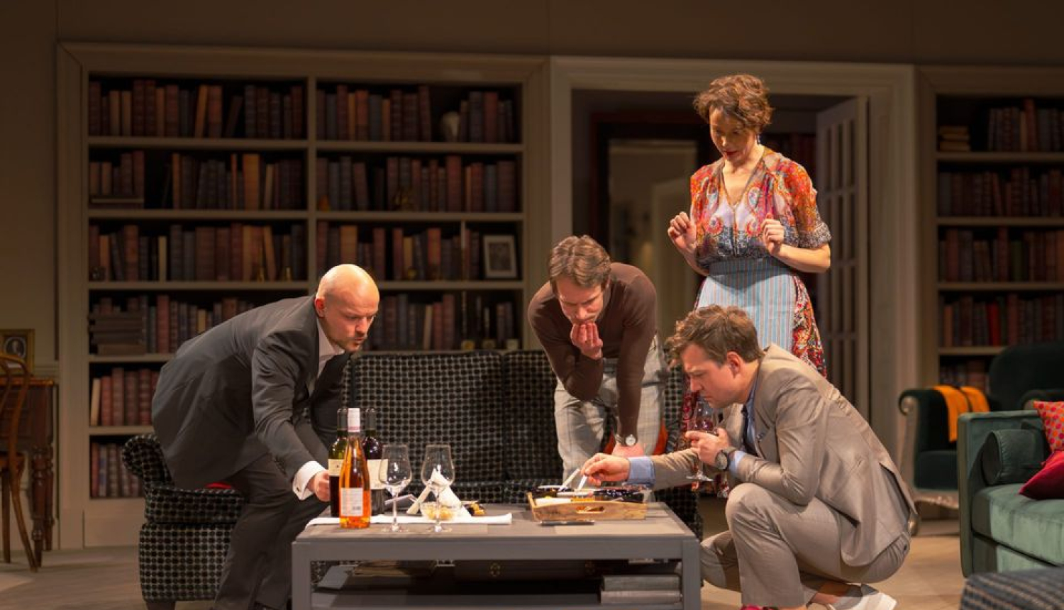 Trīs vīrieši un sieviete pēta kaut ko uz galda