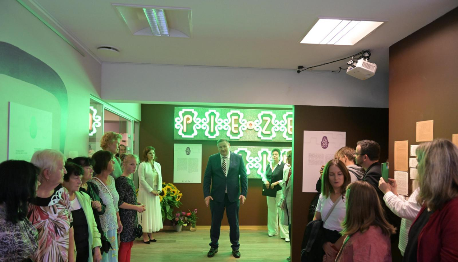 Egils Helmanis, fona uzraksts pie Zelta liepas, gar malu stāv cilvēki 23.08.2024.