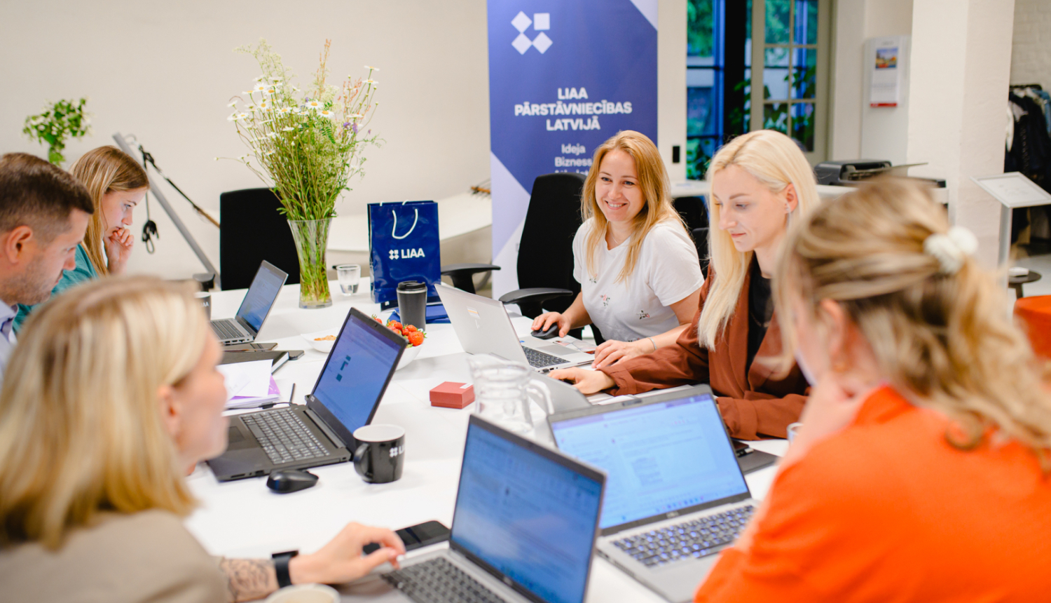 Latvijas Investīciju un attīstības aģentūras inkubācijas programmas rudens uzņemšana. Attēlā vairāki uzņēmēji ar atvērtiem planšetdatoriem, smaidīgi