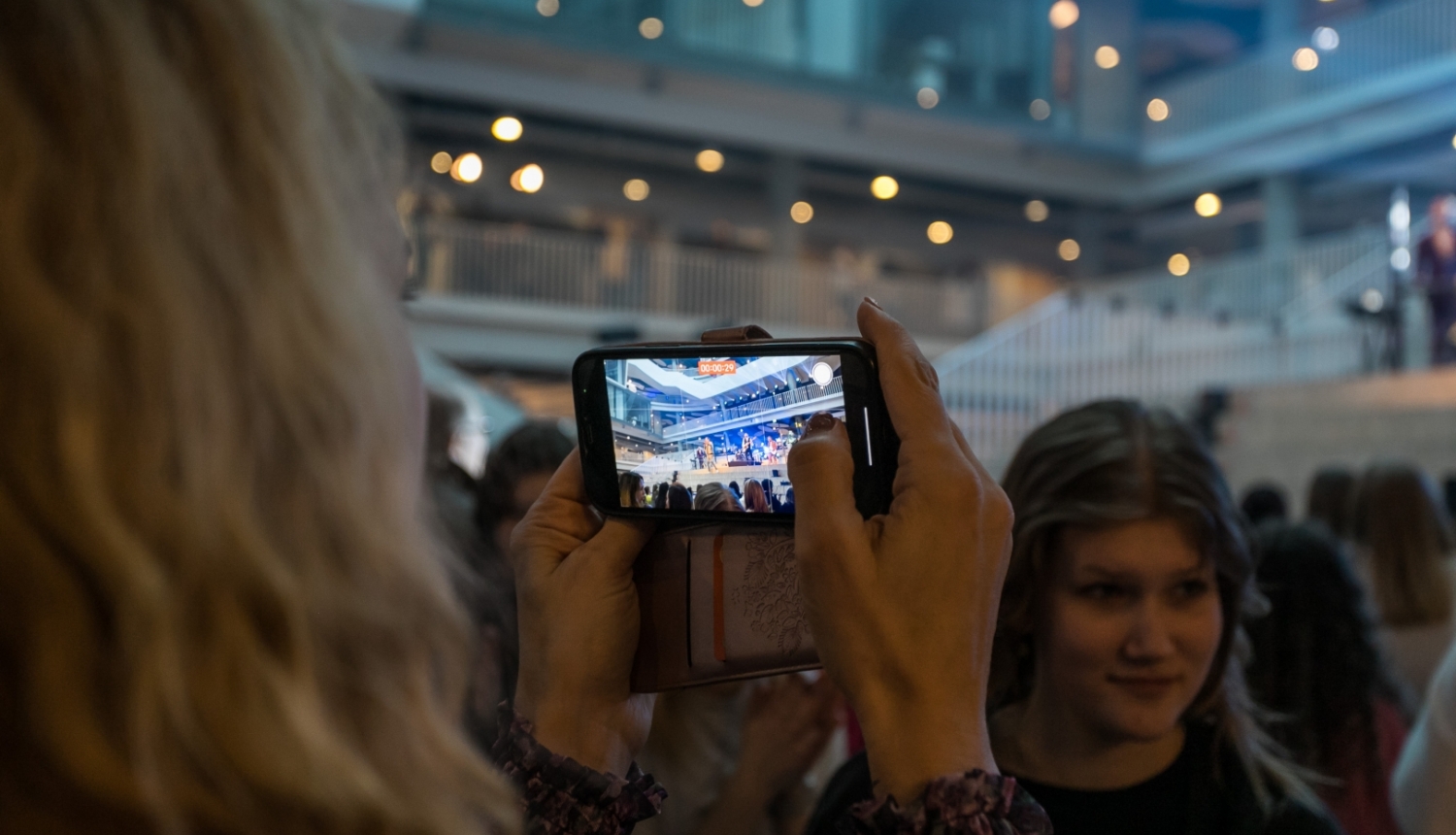 Meitene ar mobilo telefonu filmē koncertu