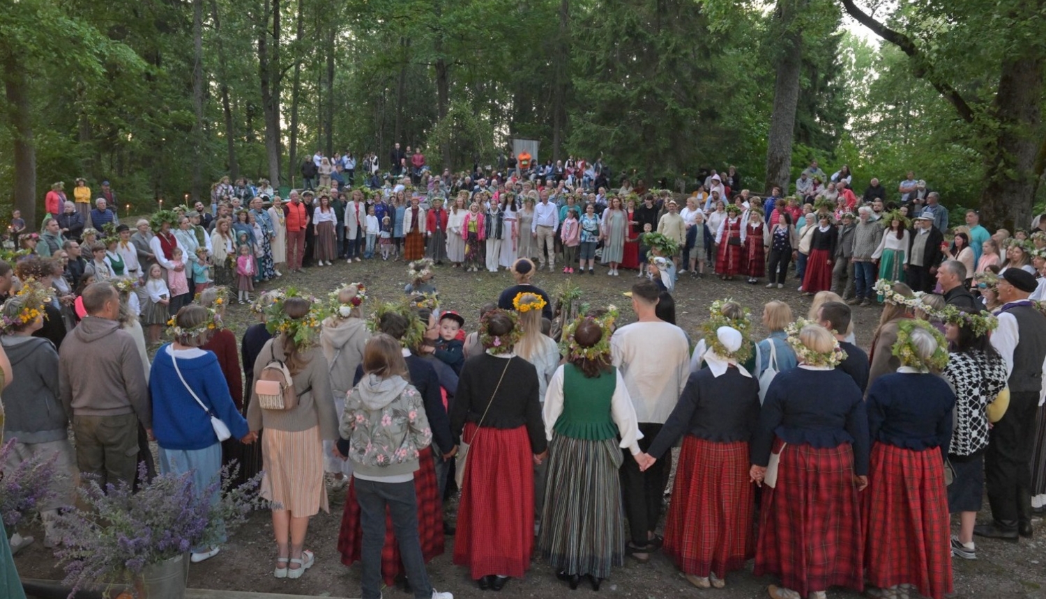 Cilvēki stāv aplī Plāteres pilskalnā 20.06.2024.