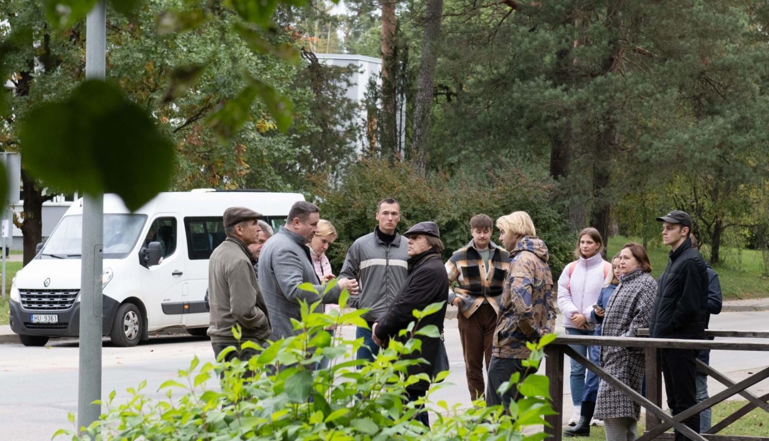 RTU profesori, studenti, Egils Helmanis stāv un sarunājas ielas malā, fonā balts mikroautobuss 09.10.2024.