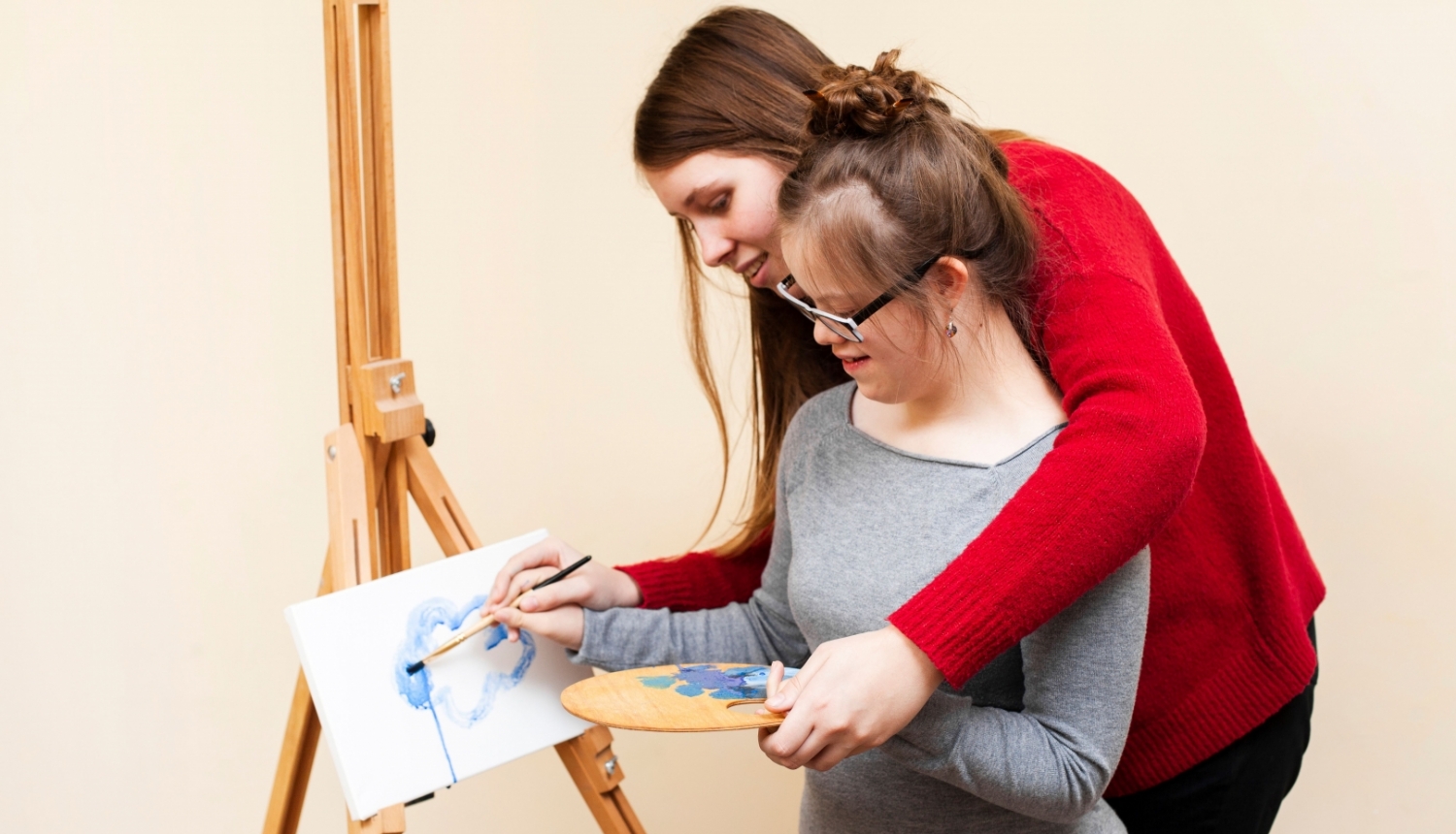 Sieviete palīdz meitenei ar īpašām vajadzībām gleznot