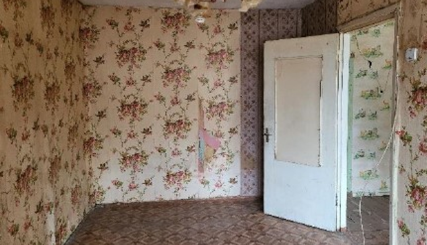 Istaba, sienas ar raibām tapetēm, baltas durvis