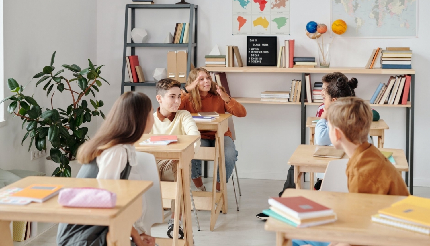 Pieci skolēni sēž klasē pie soliem