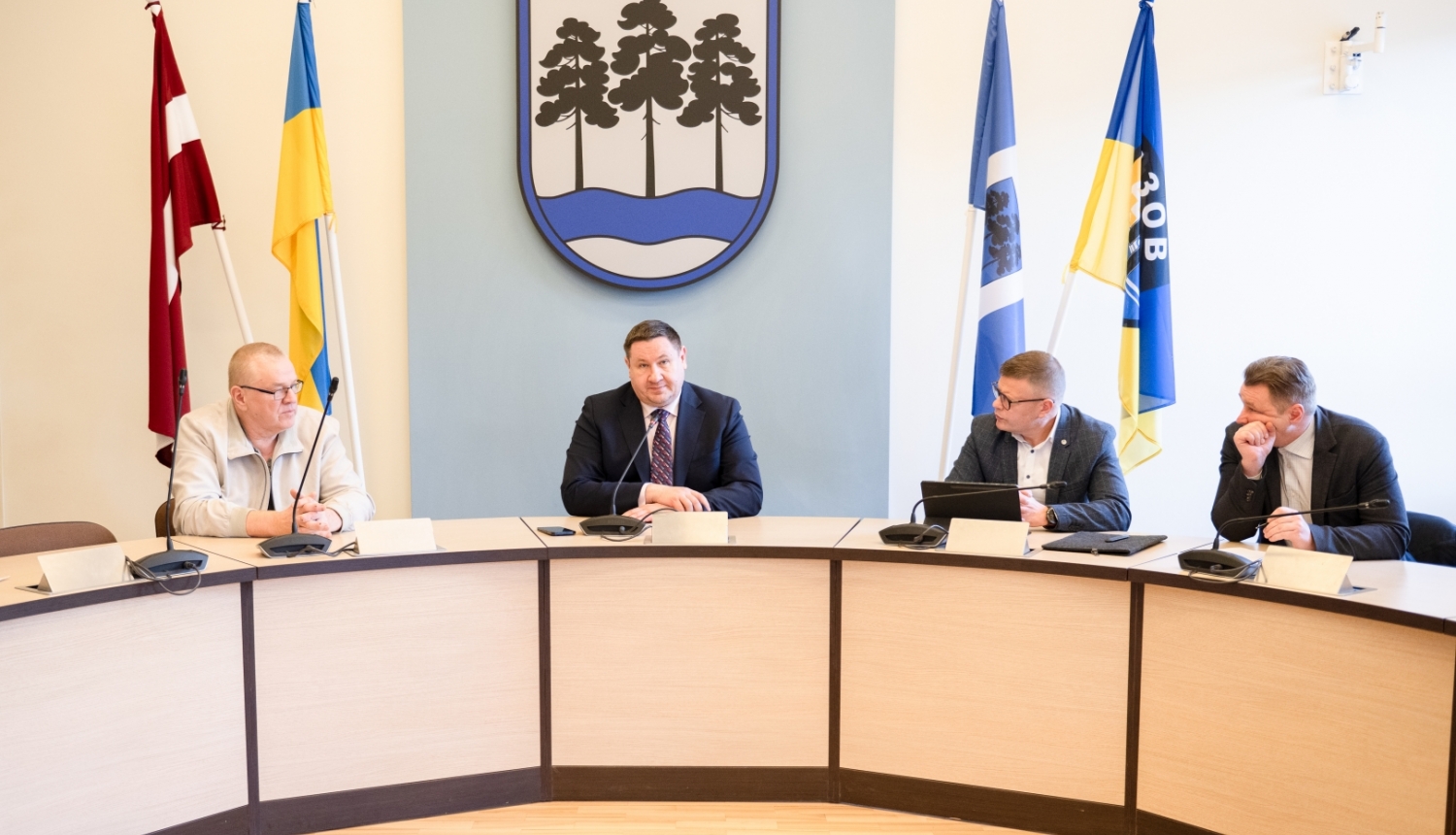 Egils Helmanis, Indulis Trapiņš un Latvijas Valsts ceļu pārstāvji sēž pie galda domes sēžu zālē