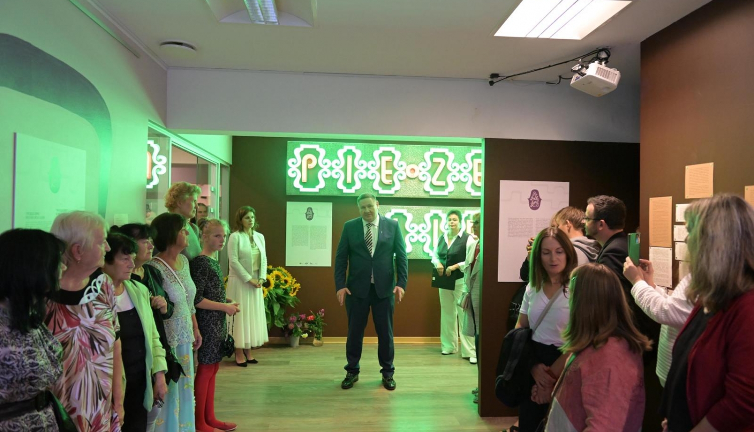 Egils Helmanis, fona uzraksts pie Zelta liepas, gar malu stāv cilvēki 23.08.2024.